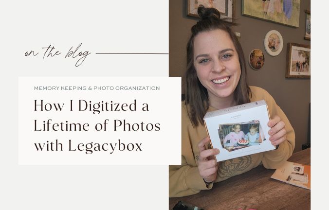 Woman smiling while holding a Legacybox photo scanning kit, surrounded by printed photos — ready to digitize a lifetime of memories.